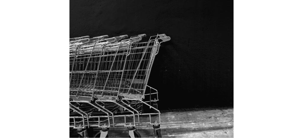 Leere Einkaufswagen vor schwarzer Wand, Symbol für das Schwinden der Nahversorger.